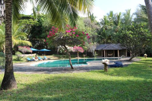 a swimming pool in a yard with palm trees at Kaskazi Beach house in Msambweni