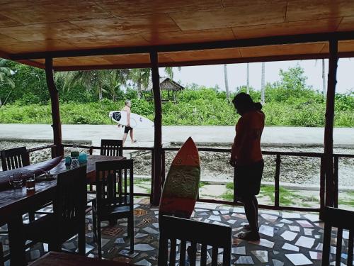 a couple of people standing in a restaurant with surfboards at Arthur Homestay Telescope Mentawai in Tuapejat