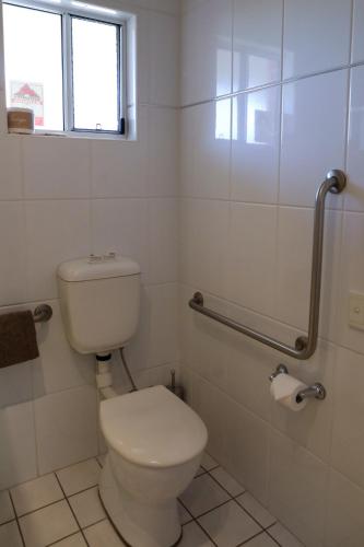 a white bathroom with a toilet and a window at Akuna Motor Inn and Apartments in Dubbo