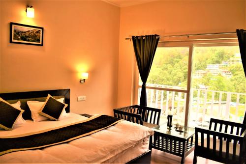 a bedroom with a bed and a large window at Hotel Vista Bhowali, Nainital - Vegetarian in Bhowāli