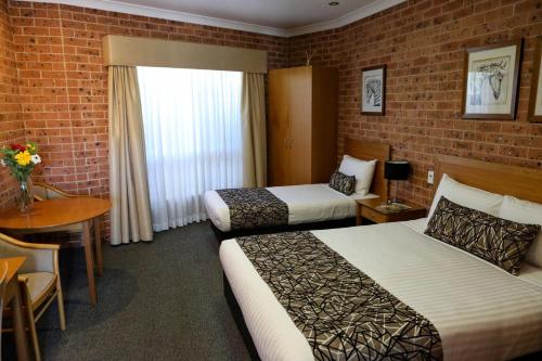 a hotel room with two beds and a table at Akuna Motor Inn and Apartments in Dubbo