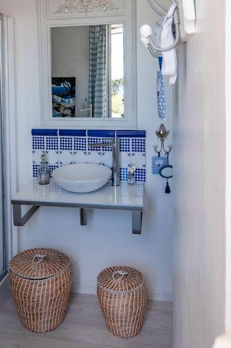 La salle de bains est pourvue d'un lavabo et de deux tabourets en osier. dans l'établissement Vue Mer Côte de Granit Rose en Bretagne, à Trébeurden