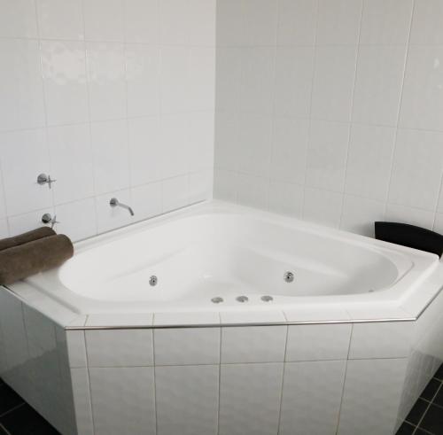 a white bath tub in a white bathroom at Akuna Motor Inn and Apartments in Dubbo