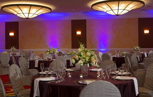 a ballroom with tables and chairs with purple lighting at Wyndham Cleveland Airport in Cleveland