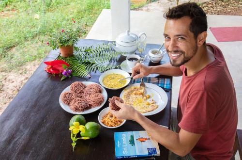 a man sitting at a table with plates of food at Sinharaja Vini Villa in Deniyaya