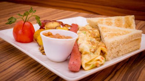 a plate of breakfast food with a sandwich and a tomato at James Court Hotel & Luxury Apartments in Lekki