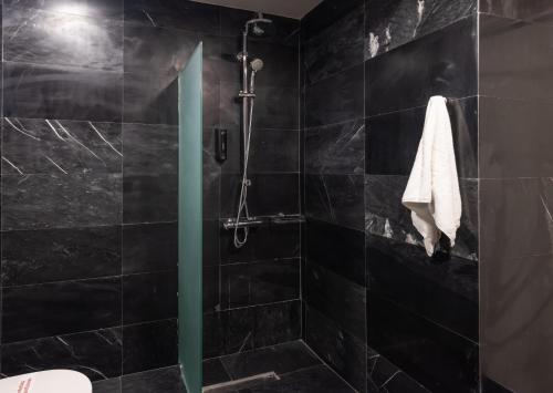 a bathroom with a shower with black tiles at Eva Mare Hotel & Suites - Adults only in Agia Pelagia