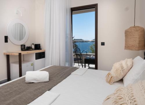 a bedroom with a large bed and a balcony at Eva Mare Hotel & Suites - Adults only in Agia Pelagia
