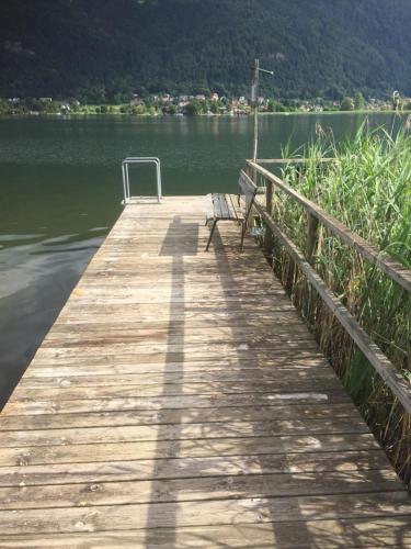 a wooden pier with a bench on the water at Seechalet in Altossiach