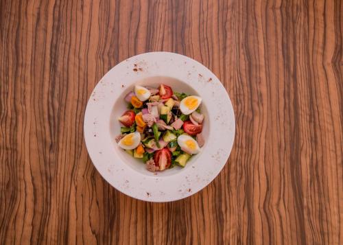 a bowl of salad with eggs and tomatoes on a wooden table at James Court Hotel & Luxury Apartments in Lekki