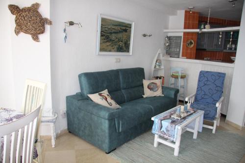 a living room with a green couch and a table at Primera Linea de Playa con Garaje in Calpe