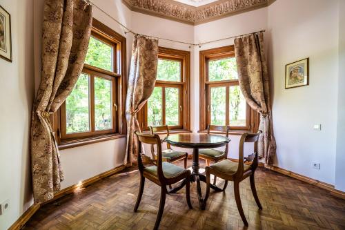 a dining room with a table and chairs and windows at Villa Apartments by the sea in Liepāja