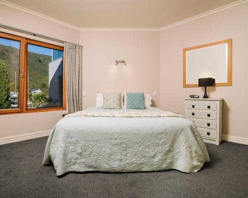 a white bedroom with a bed and a window at Wilkes Way Villa in Picton