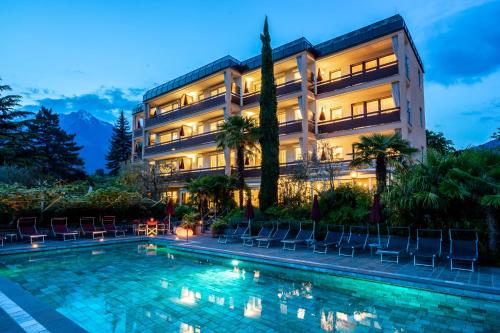 a hotel with a swimming pool in front of a building at Hotel Gartenresidence Zea Curtis in Merano