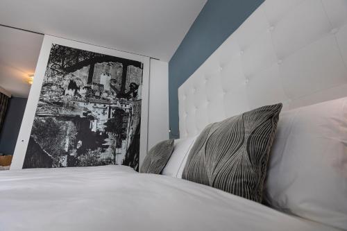 a bedroom with a white bed with a picture on the wall at Hotel Capri in Malcesine