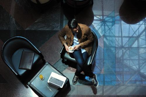 a man sitting in a chair in front of a table with a laptop at Hotel Mercure Alger Aéroport in Dar el Beïda
