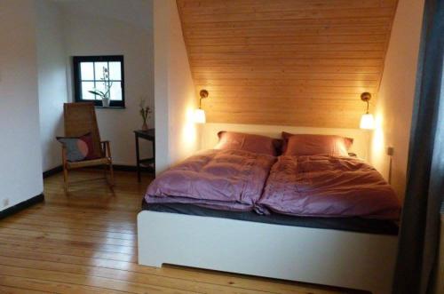 a bedroom with a bed with a wooden wall at Darßer Strandgut - Haus Butzek in Ahrenshoop