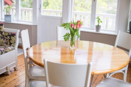 a dining room table with a vase of flowers on it at Sörtorpets gårdshus in Älvkarleby