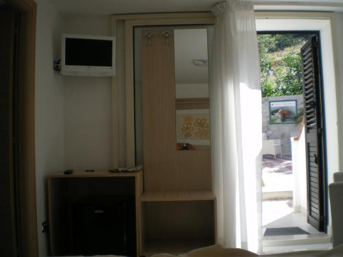 Habitación con puerta corredera de cristal y TV. en B&B Ala Marina, en Peschici