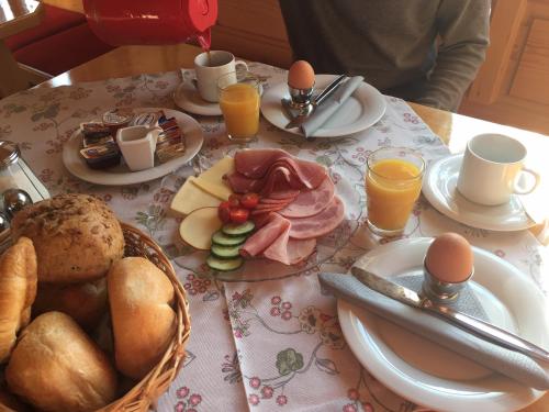 Una mesa con un desayuno de huevos, jamón y pan. en Pension Zum Rechen, en Bodenmais