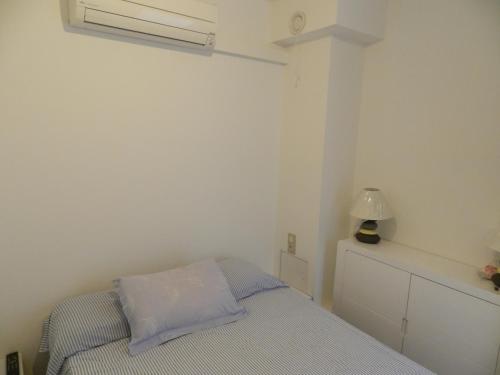 Dormitorio pequeño con cama y lámpara en Front de mer T2 PALAVAS LES FLOTS direct plage, en Palavas-les-Flots
