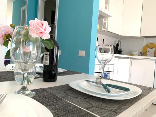 カレタ・デ・フステにあるNew Apartment Sun beachの皿付きテーブル、グラス2杯、ピンクのバラ