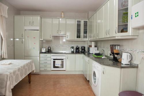 a kitchen with white cabinets and white appliances at La Rosaleda de Orgaz in Orgaz
