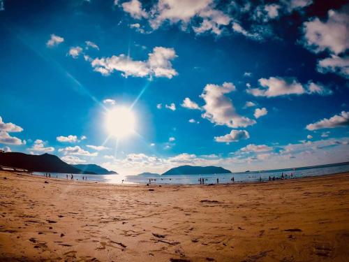 a group of people on a beach with the sun at Hoàng Gia Hotel Côn Đảo in Con Dao