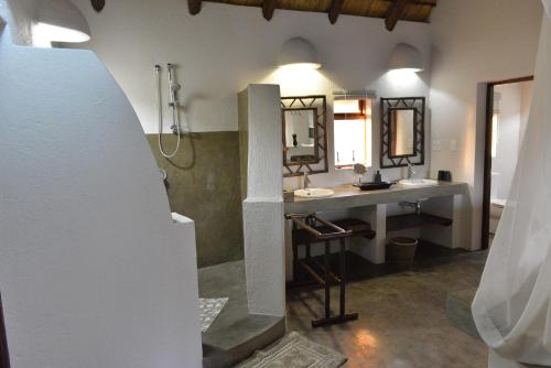 a bathroom with two sinks and two mirrors at Wildlife Estate House With Mountain Views & 12-Meter Pool in Hoedspruit