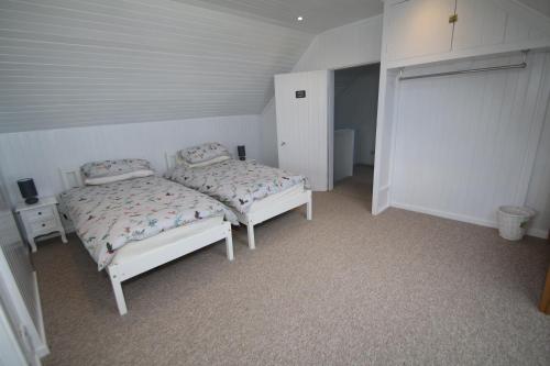 a bedroom with two beds in a white room at Arle Farmhouse in Tobermory