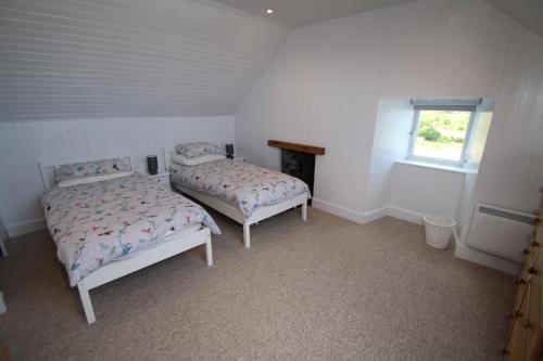 a bedroom with two beds and a window at Arle Farmhouse in Tobermory