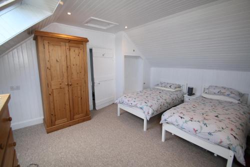 a bedroom with two beds and a wooden cabinet at Arle Farmhouse in Tobermory