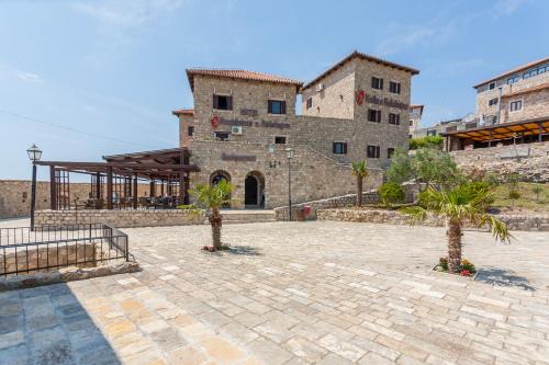 a building with two palm trees in a courtyard at Hotel Kulla e Balshajve in Ulcinj