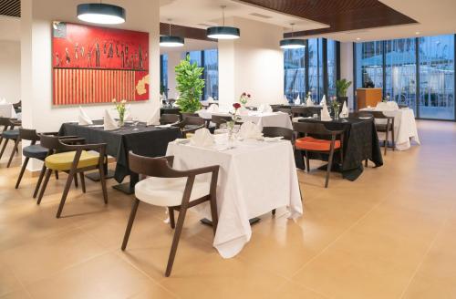a restaurant with tables and chairs with white table cloth at Golden Tulip Royaume in Alger