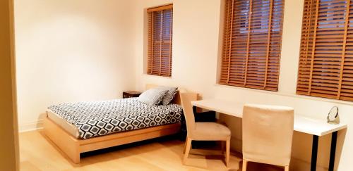 a bedroom with a bed and a desk and windows at Covent Garden Penthouse in London