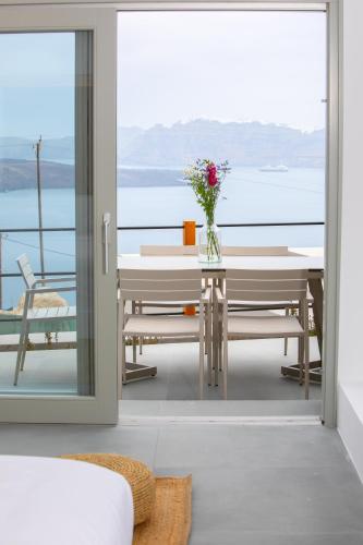a dining room with a table and a view of the water at Melidonia Suites in Akrotiri
