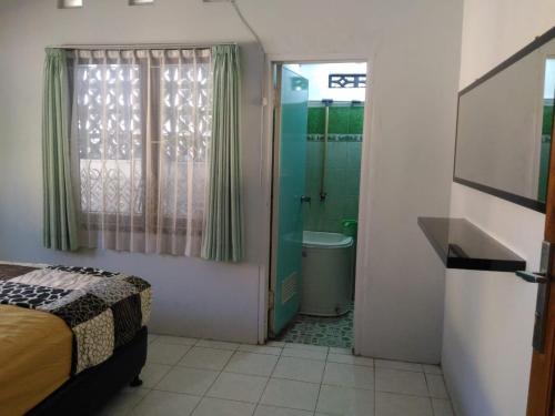 ein Schlafzimmer mit einem Bett und ein Badezimmer mit einer Dusche in der Unterkunft Herry Home Stay_Jogja in Yogyakarta