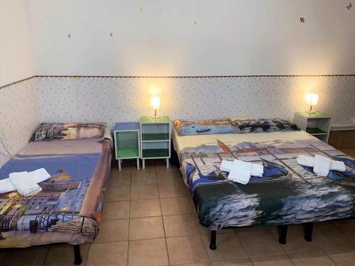 two beds in a room with two tables and two lamps at Pavarotti House in Venice