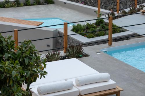 a pool with two lounge chairs next to a swimming pool at Melidonia Suites in Akrotiri