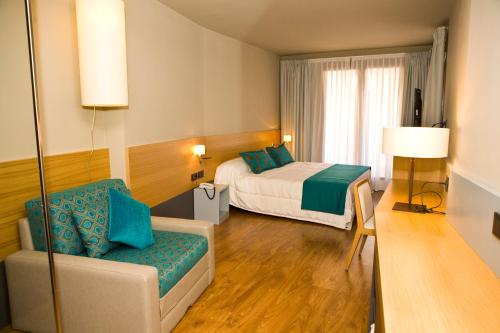 CinctorresにあるEl Faixero Evolucionのベッドとソファ付きの広いホテルルームです。