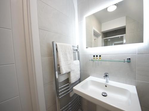 a white bathroom with a sink and a mirror at Grand Hotel Swanage in Swanage
