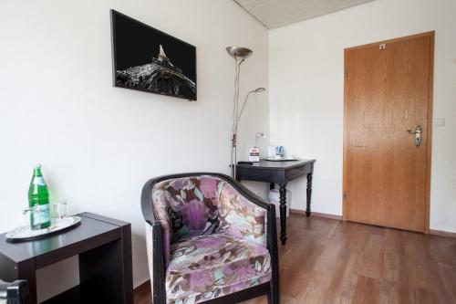a room with a chair and a desk and a lamp at Hotel Nassauer Hof in Wissen