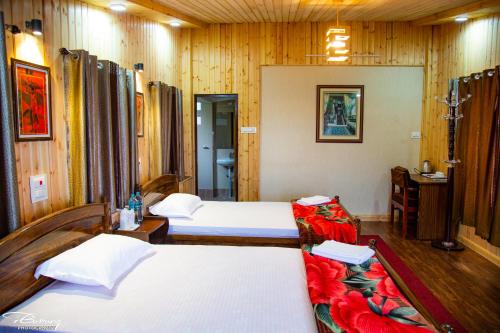 two beds in a room with wooden walls at Dreamhome Stay in Kurseong