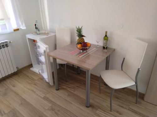 a table with a bowl of fruit and a bottle of wine at Apartmani Sara i Marta in Otočac