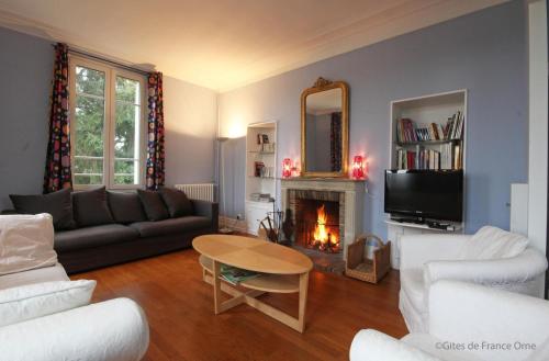 a living room with a couch and a table and a fireplace at Normandie 12 couchages in LʼAigle