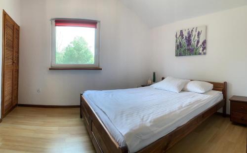sypialnia z dużym łóżkiem i oknem w obiekcie Domki Magnolia w Dźwirzynie