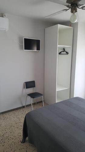 - une chambre avec un lit, une chaise et un ventilateur de plafond dans l'établissement Hostal Can Joanet, à Cambrils