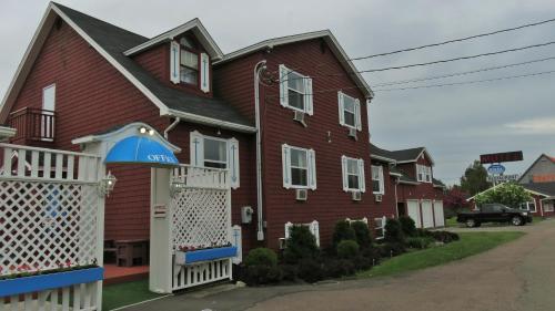 a large red house with a white gate at Hopewell Rocks Motel & Country Inn in Hopewell Cape