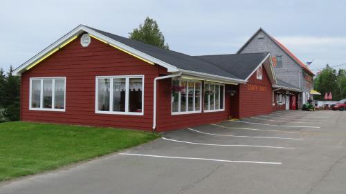 a red building with white windows in a parking lot at Hopewell Rocks Motel & Country Inn in Hopewell Cape