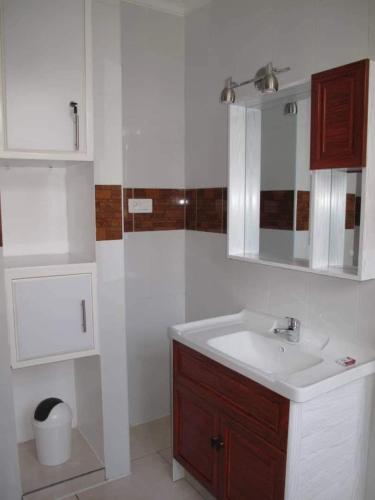 a white bathroom with a sink and a mirror at Hôtel Maisons-Sifa in Butare
